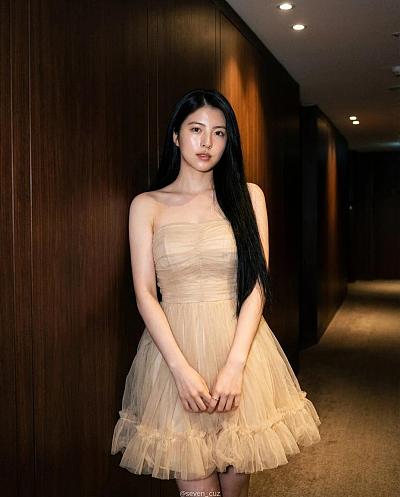 优雅女性身着香槟色礼服倚墙而立