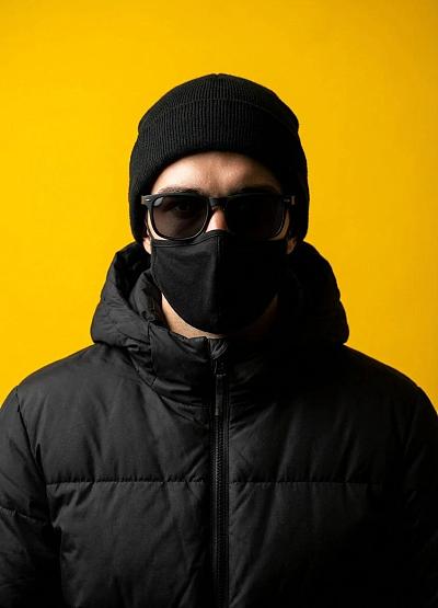 黑衣男子戴帽墨镜口罩，黄背景时尚肖像照