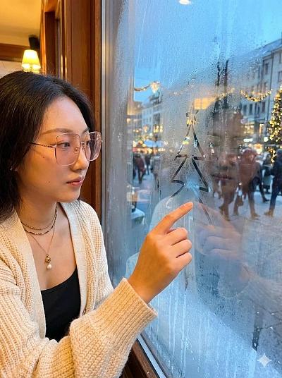窗边画圣诞树的女子