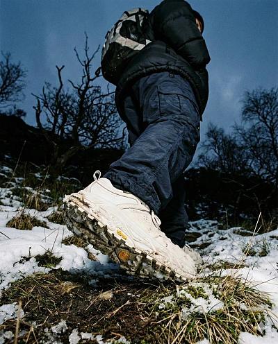 高阶户外机能风雪地徒步摄影，聚焦鞋底与粗犷自然细节