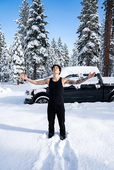 雪林中青年男子张臂仰望天空，展现自由与宁静
